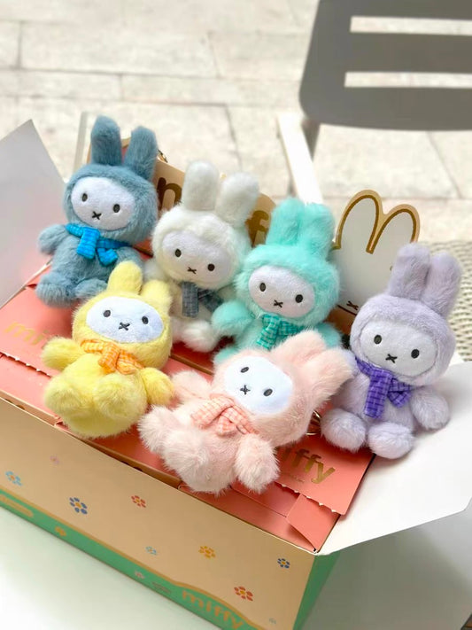 Colorful fluffy bunny plush keychains in blue, white, mint, yellow, pink, and lavender on a decorated box, pop mart style